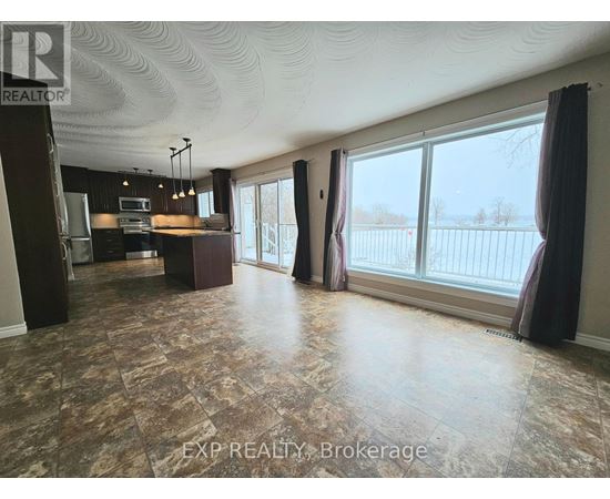 A spacious room with a large window and a view of a fence.