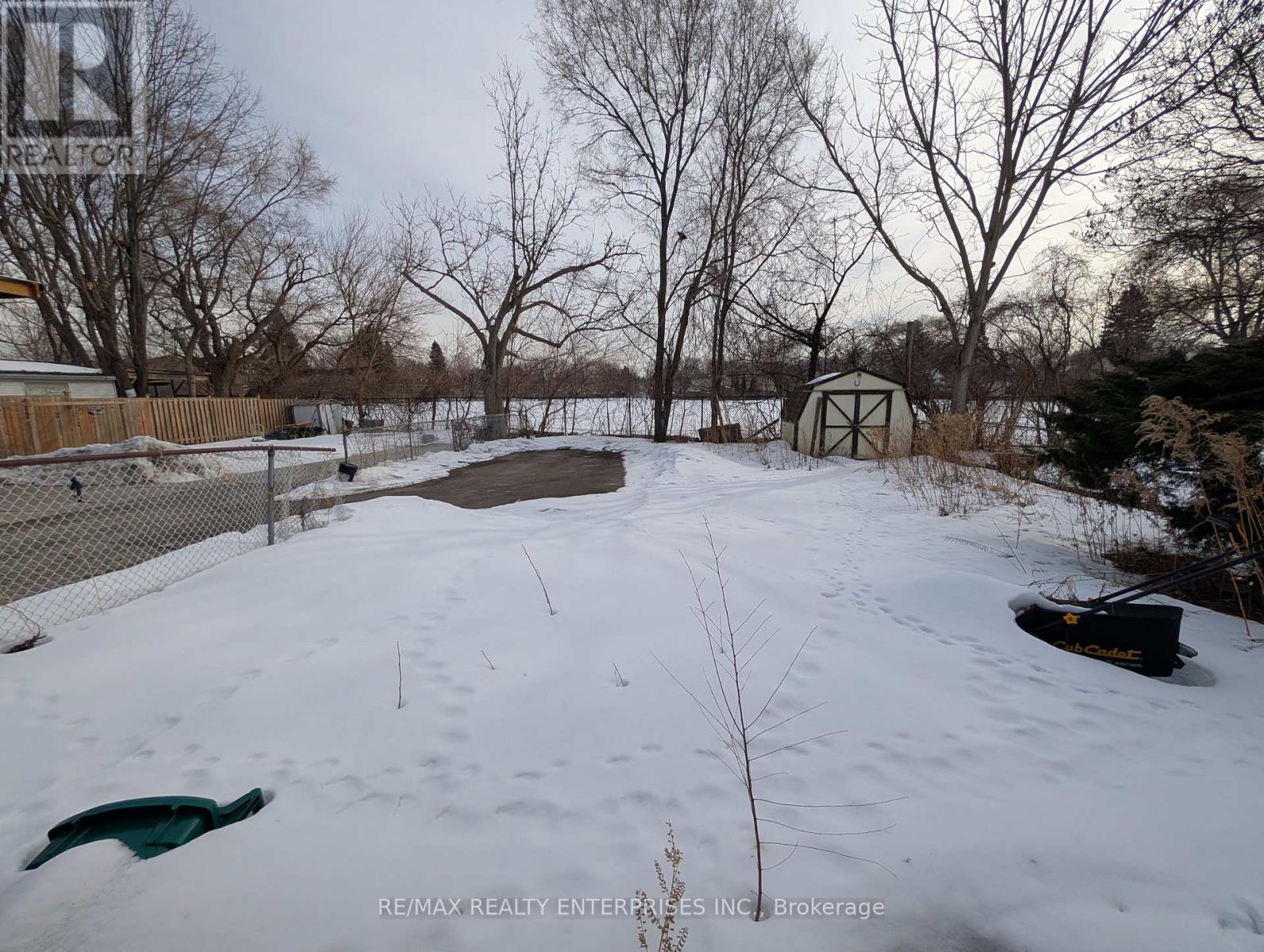 A snow-covered field with a fence and trees in the background.