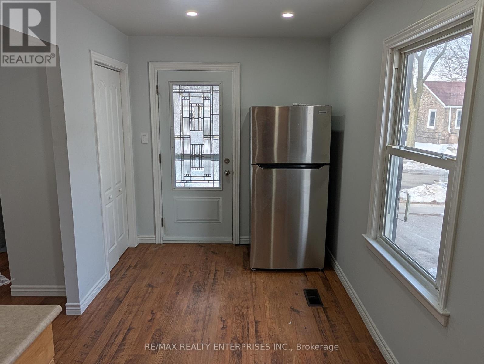 A room with a stainless steel refrigerator and a door with a window.