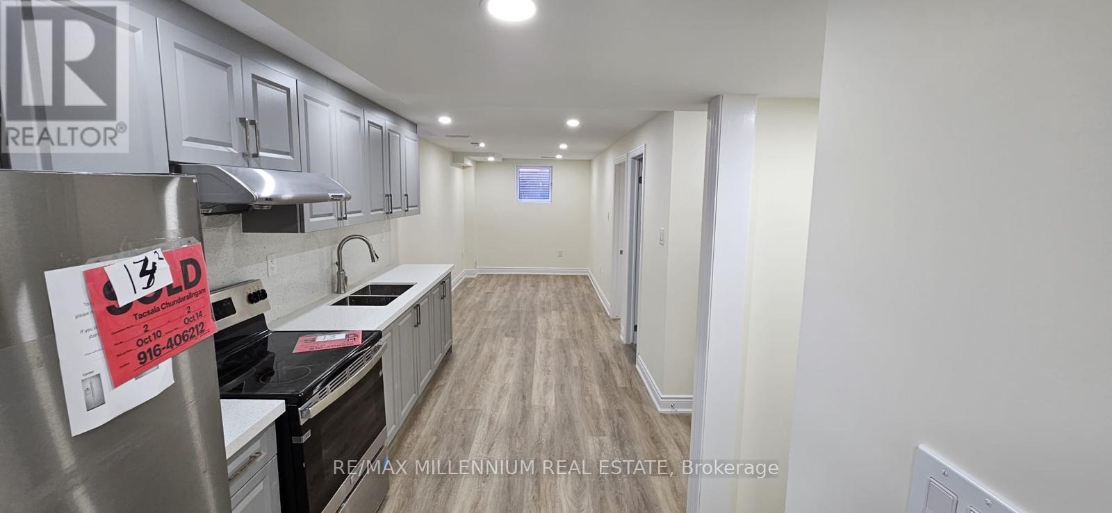 A kitchen with a stove top oven and a refrigerator with a sign on it.