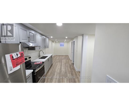 A kitchen with a stove top oven and a refrigerator with a sign on it.