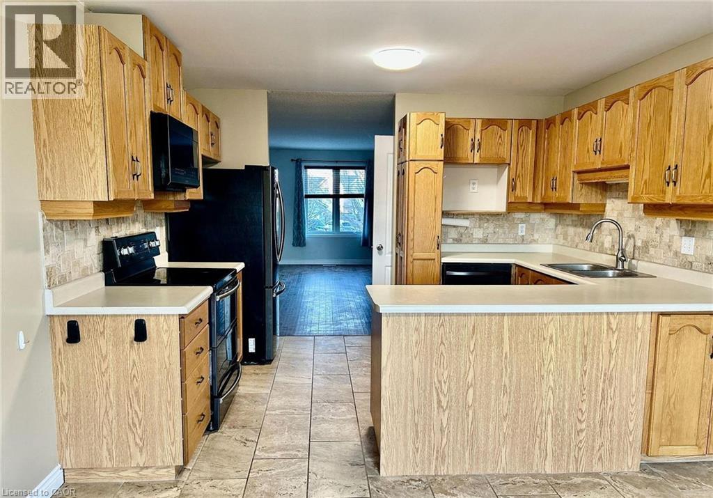 A kitchen with wooden cabinets and a black refrigerator.