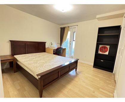 A bedroom with a large bed and a wooden headboard.