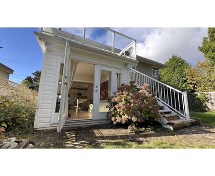 A small white house with a glass door and a staircase leading to the entrance.