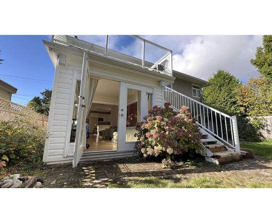 A small white house with a glass door and a staircase leading to the entrance.