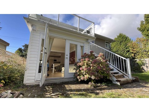 A small white house with a glass door and a staircase leading to the entrance.