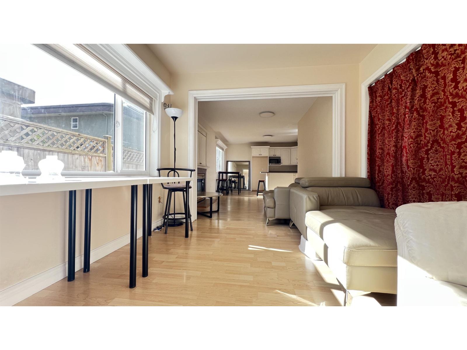 A living room with a white couch and a dining table with chairs.