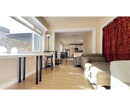 A living room with a white couch and a dining table with chairs.