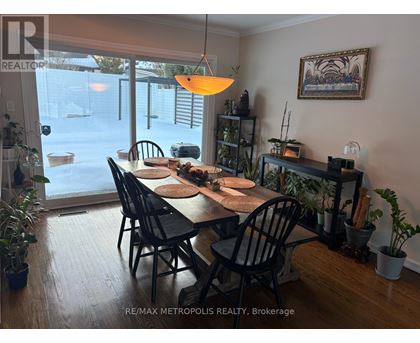A dining room with a table set for six with a view of the backyard.