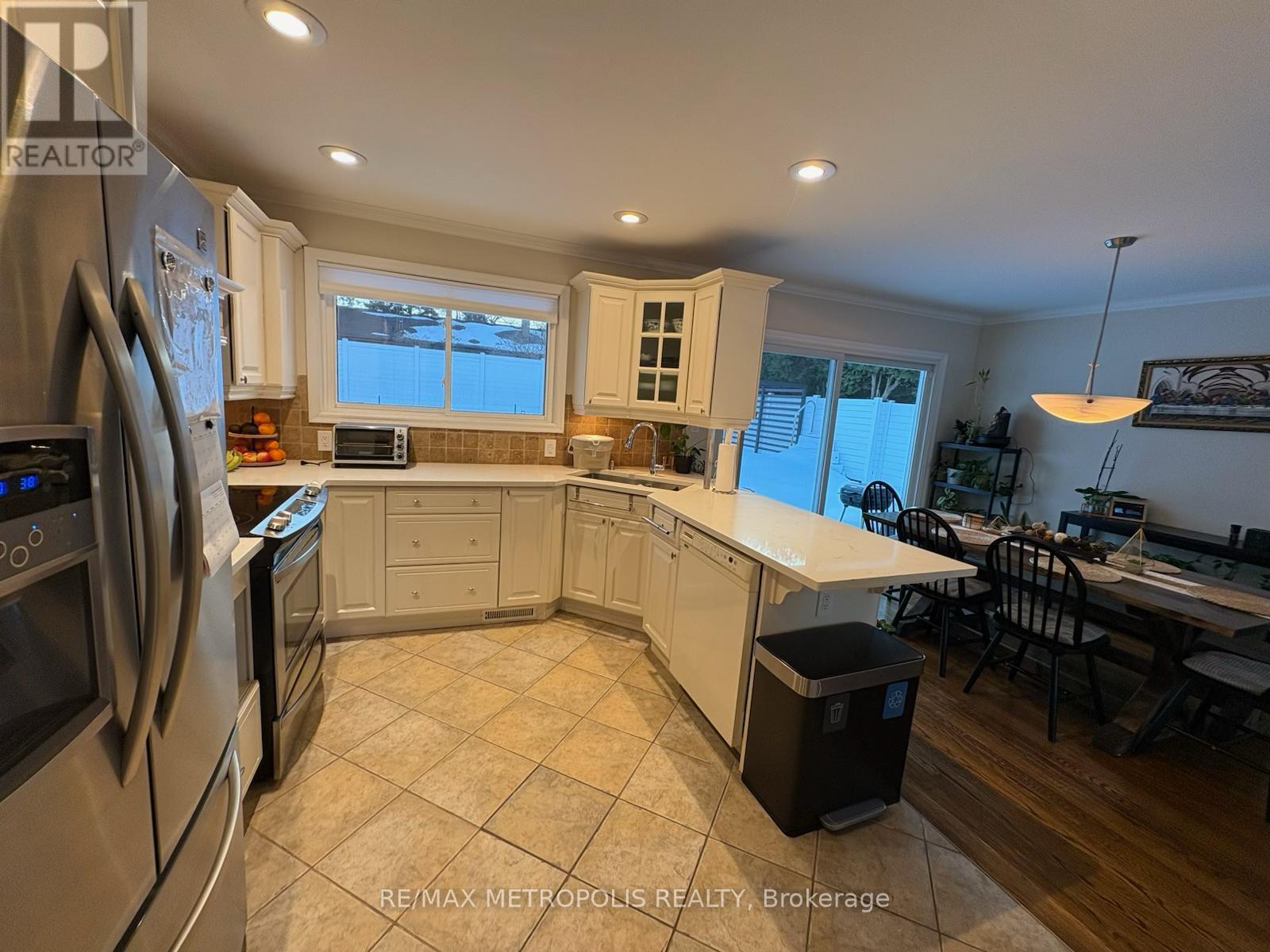 A kitchen with a refrigerator, oven, microwave, and a dining table with chairs.