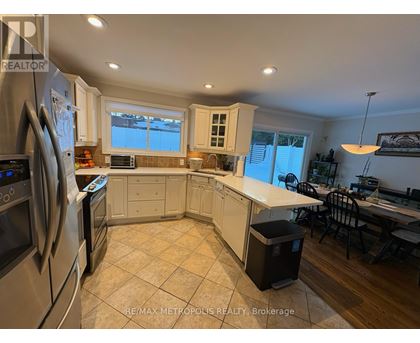 A kitchen with a refrigerator, oven, microwave, and a dining table with chairs.