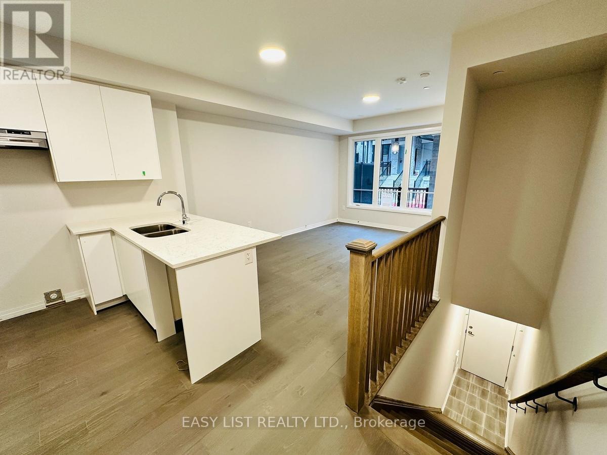 A kitchen with white cabinets and a wooden staircase.