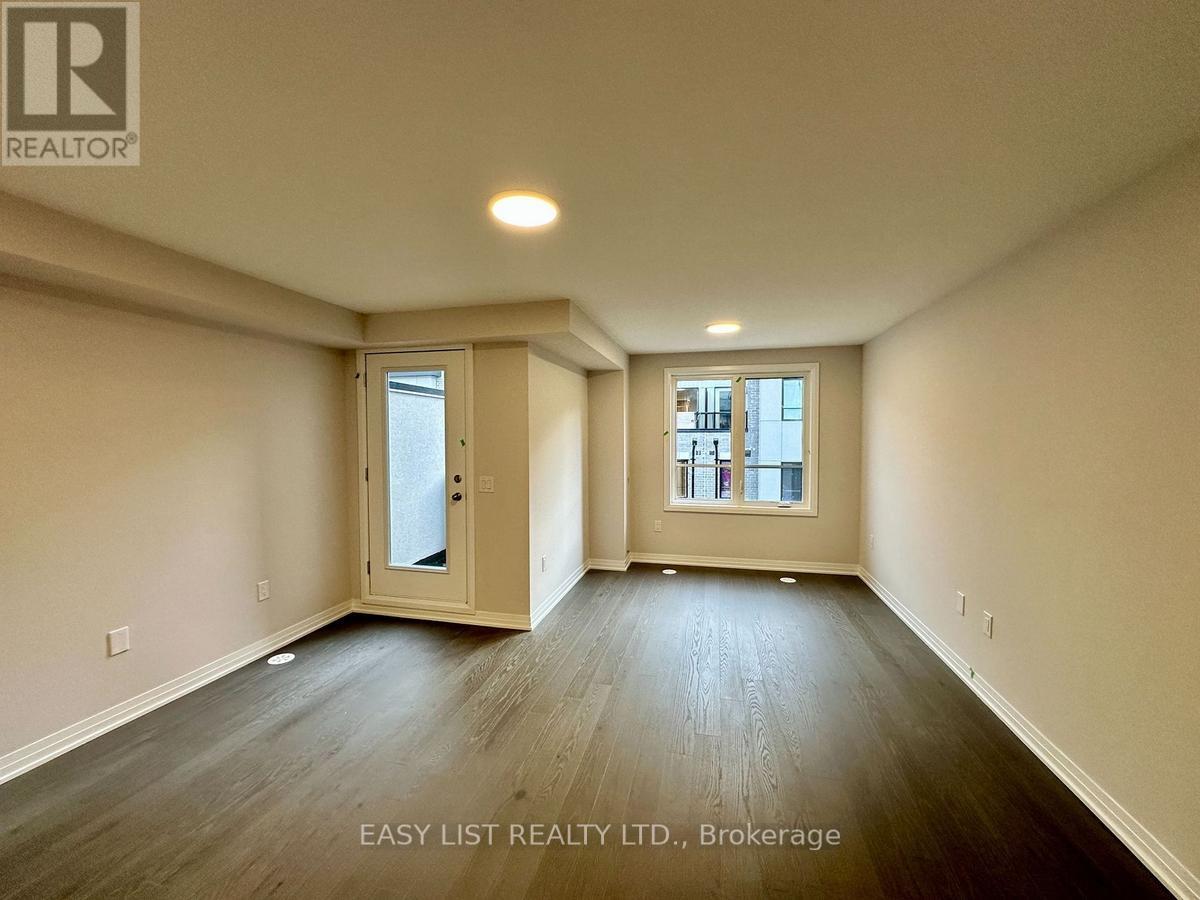 A spacious room with wooden floors and a large window.