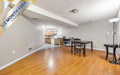 A dining room with a table set for two and a kitchen in the background.