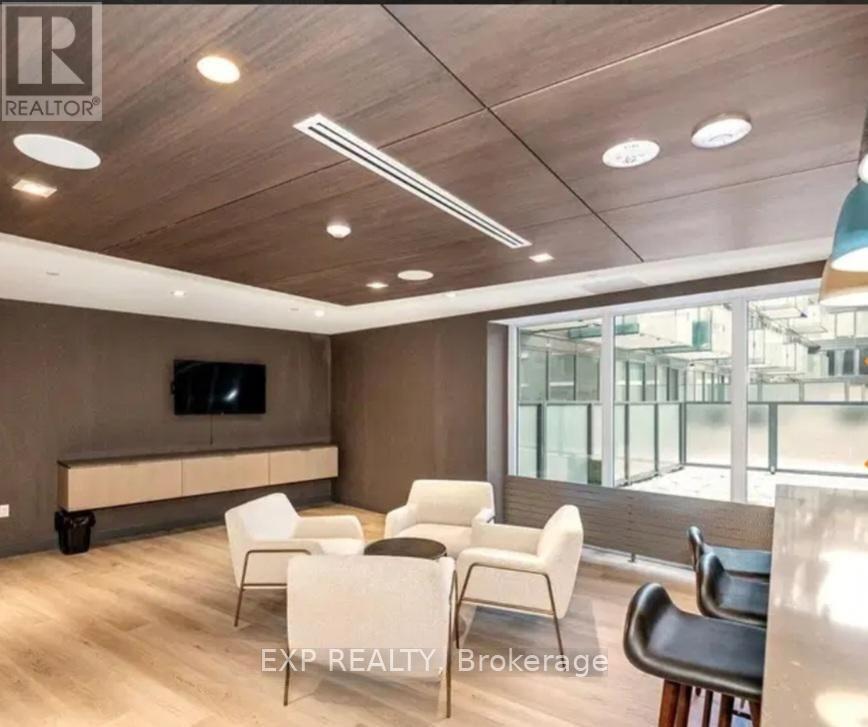 A living room with a flat screen TV and a row of chairs.