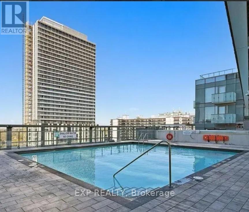 A pool area with a glass railing and a tall building in the background.