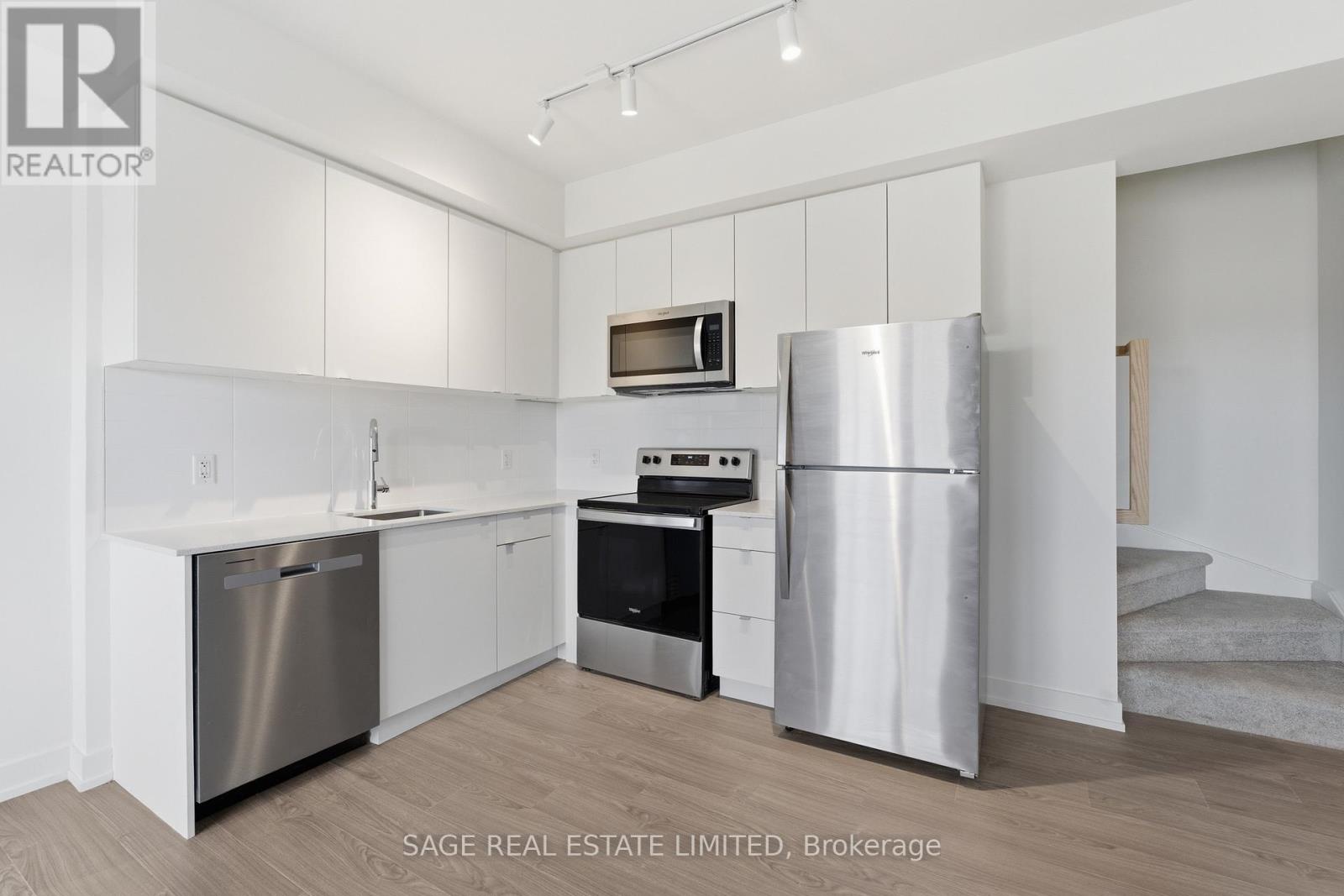 A white kitchen with a refrigerator, stove, and dishwasher.