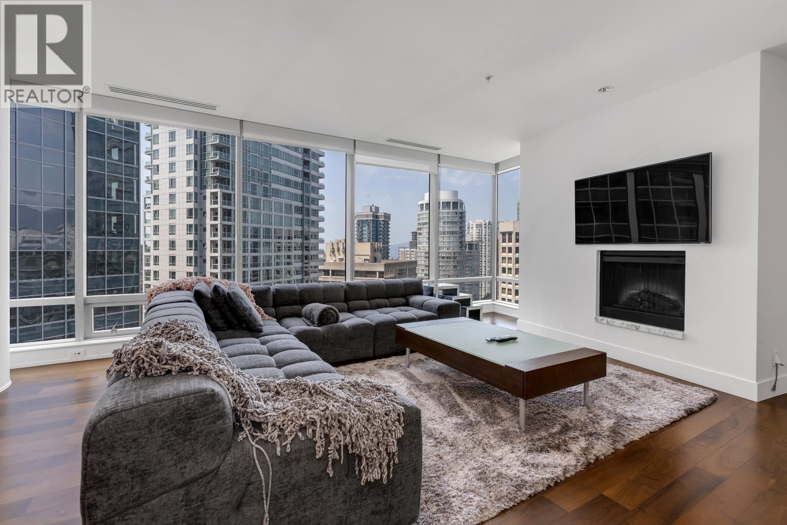 A living room with a grey couch and a fireplace.