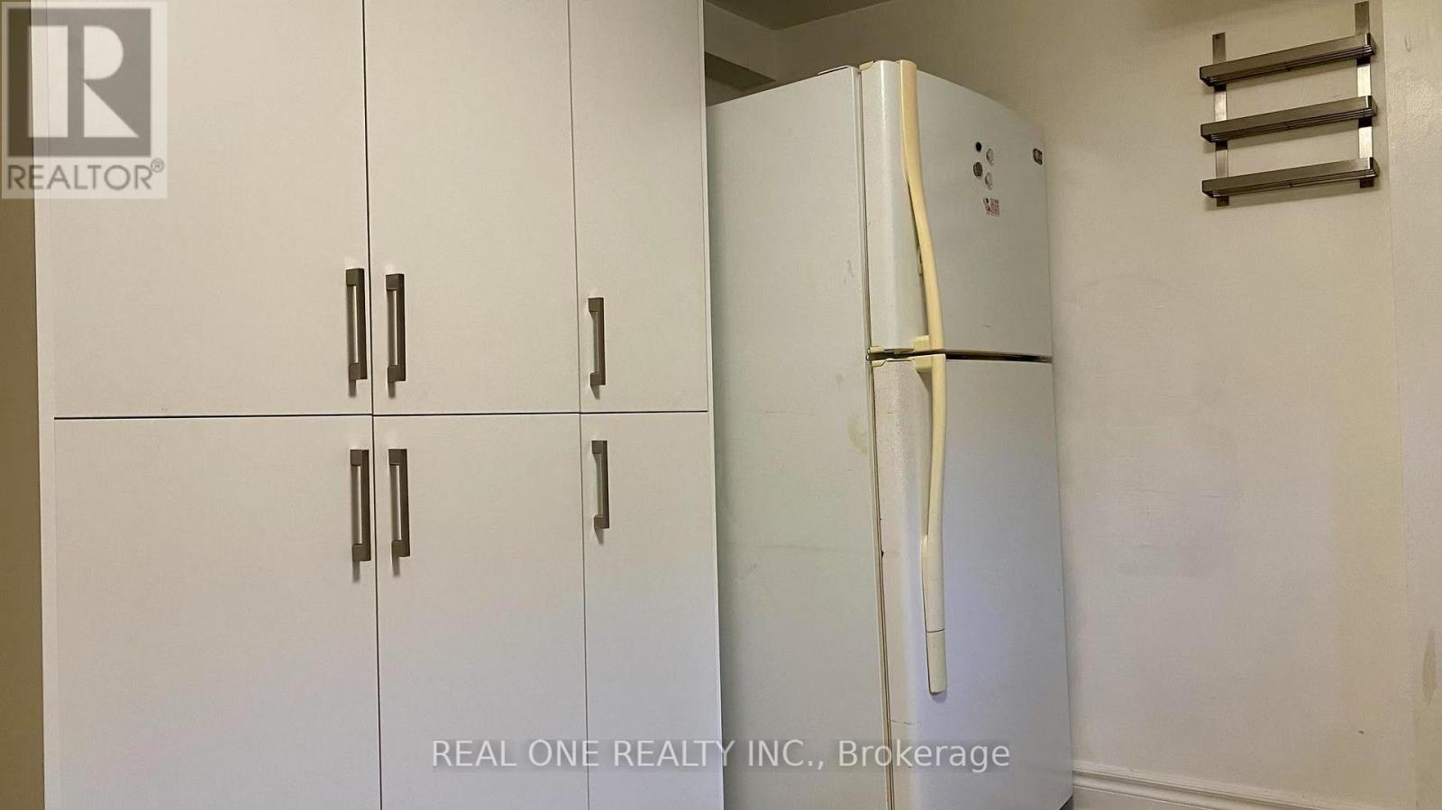 A white refrigerator with a yellow tape on it is in a room with white walls.