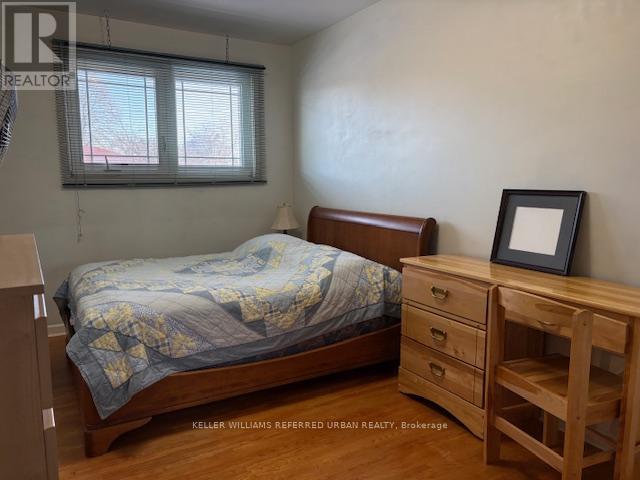 A bedroom with a bed, nightstand, and a wooden dresser.