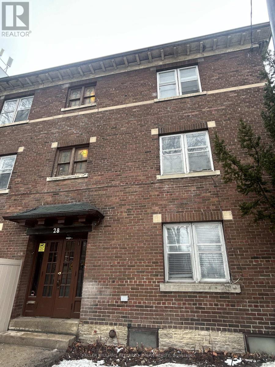 A brown brick building with a black awning and a yellow sign on the door.