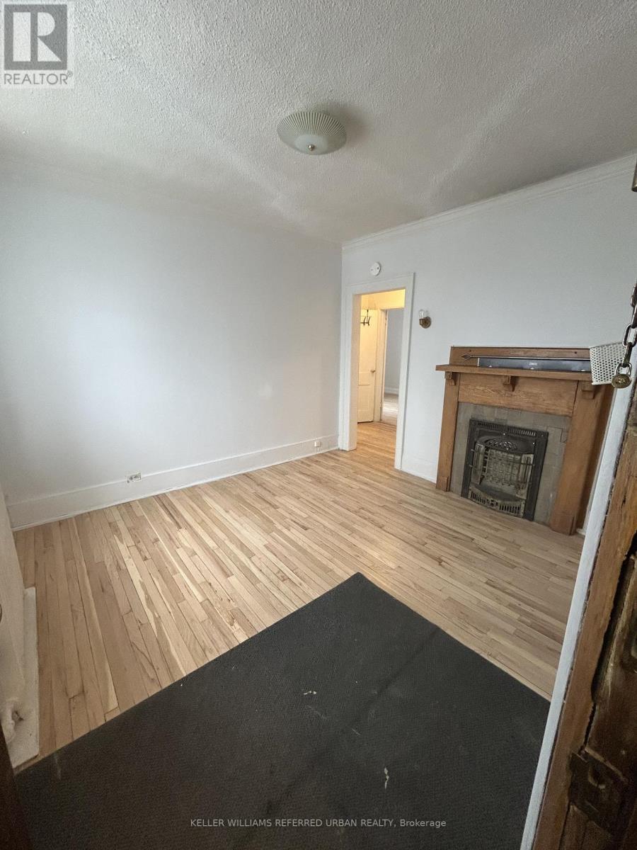 A room with a fireplace and wood flooring.