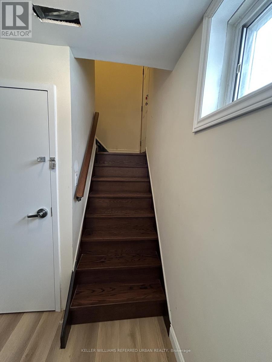 A staircase with a white door on the left and a window on the right.