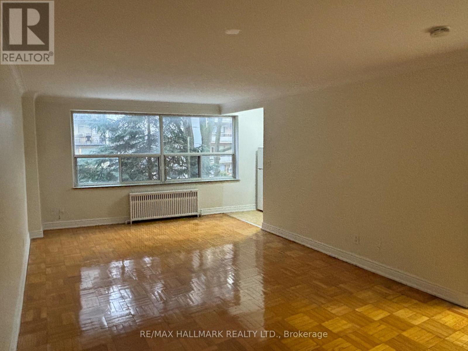 A room with a large window and a radiator on the wall.