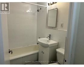 A white bathroom with a sink, toilet and bathtub.