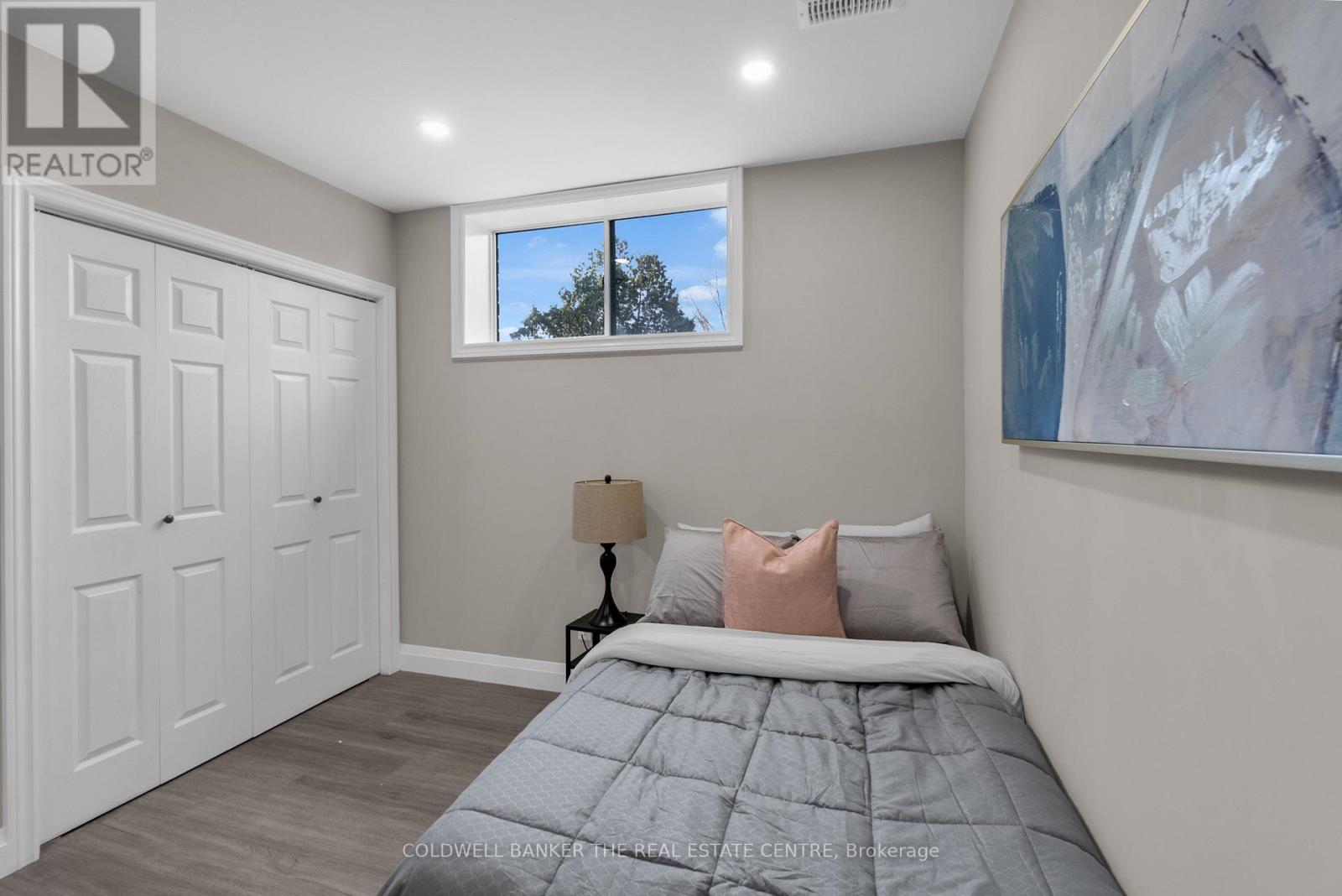 A bedroom with a large bed and a painting on the wall.