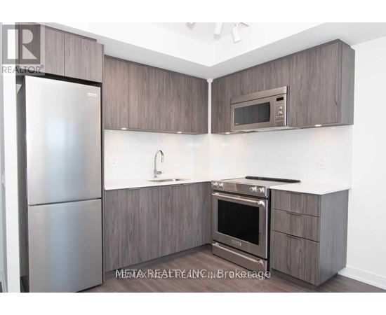A modern kitchen with a refrigerator, oven, microwave, and sink.