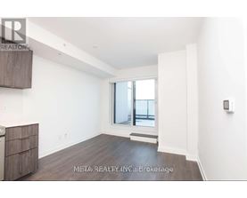 A spacious, empty room with a window and a wooden floor.