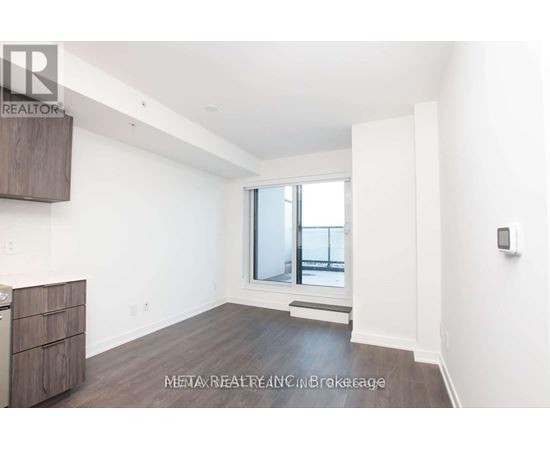 A spacious, empty room with a window and a wooden floor.