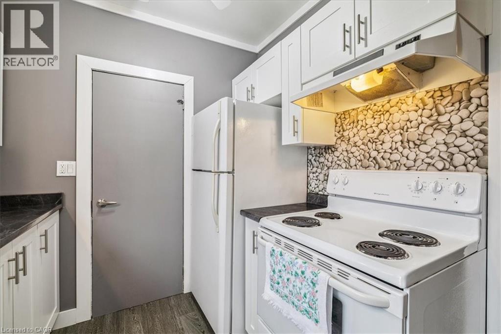 A white stove in a kitchen with a stone backsplash.