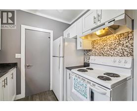 A white stove in a kitchen with a stone backsplash.