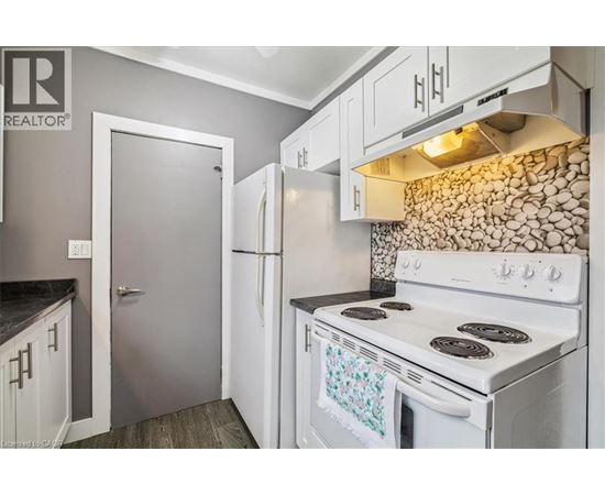 A white stove in a kitchen with a stone backsplash.