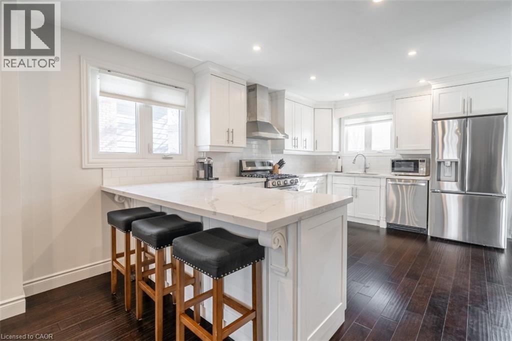 A kitchen with white cabinets and a white island with black bar stools.