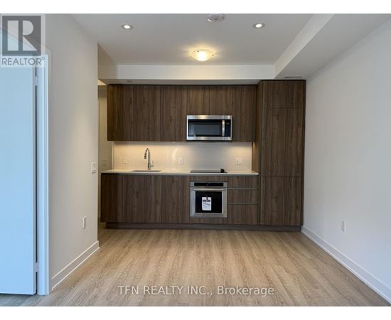 A modern kitchen with wooden cabinets and a microwave above the stove.