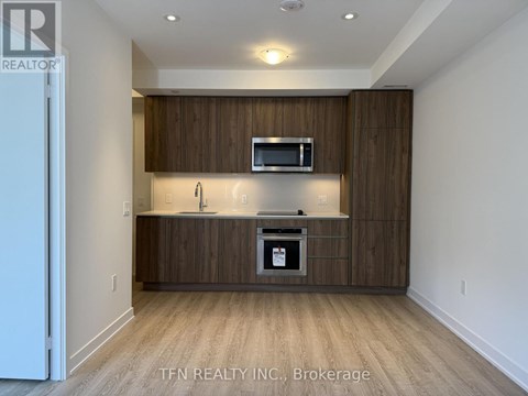 A modern kitchen with wooden cabinets and a microwave above the stove.