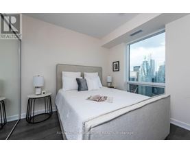 A bedroom with a large bed and a city view through the window.