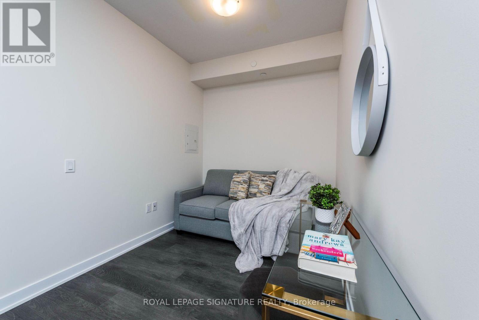 A living room with a grey couch and a round mirror on the wall.