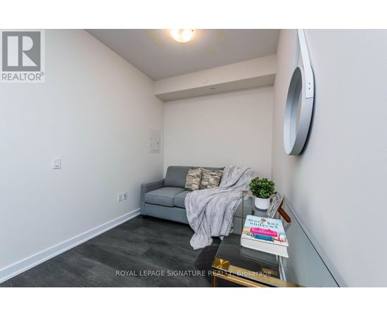 A living room with a grey couch and a round mirror on the wall.