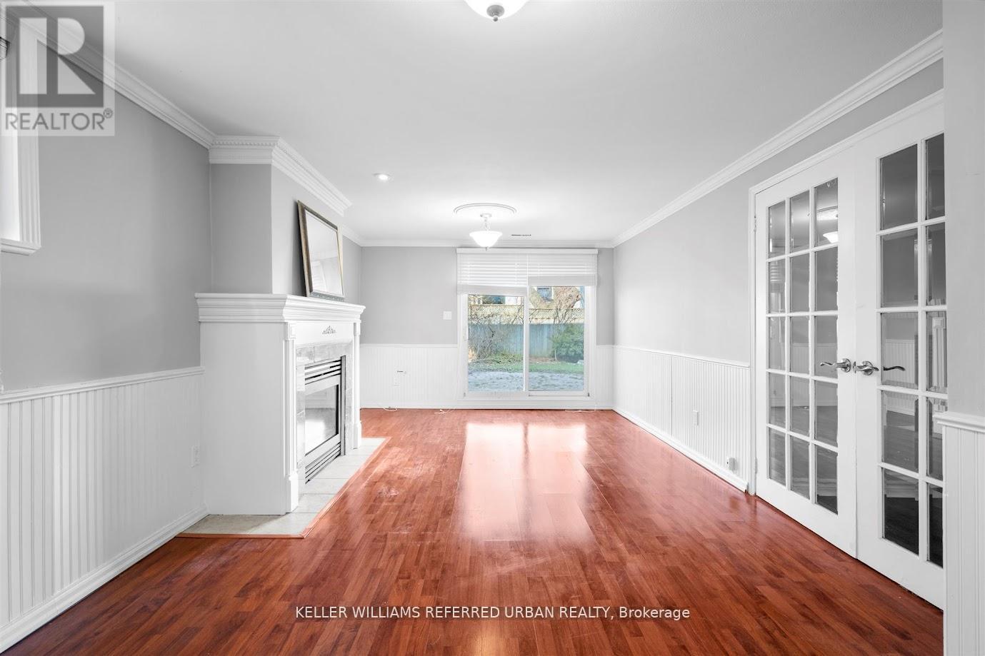 A spacious room with wood flooring and white walls.