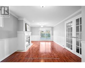 A spacious room with wood flooring and white walls.