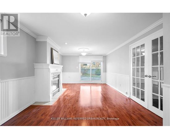 A spacious room with wood flooring and white walls.