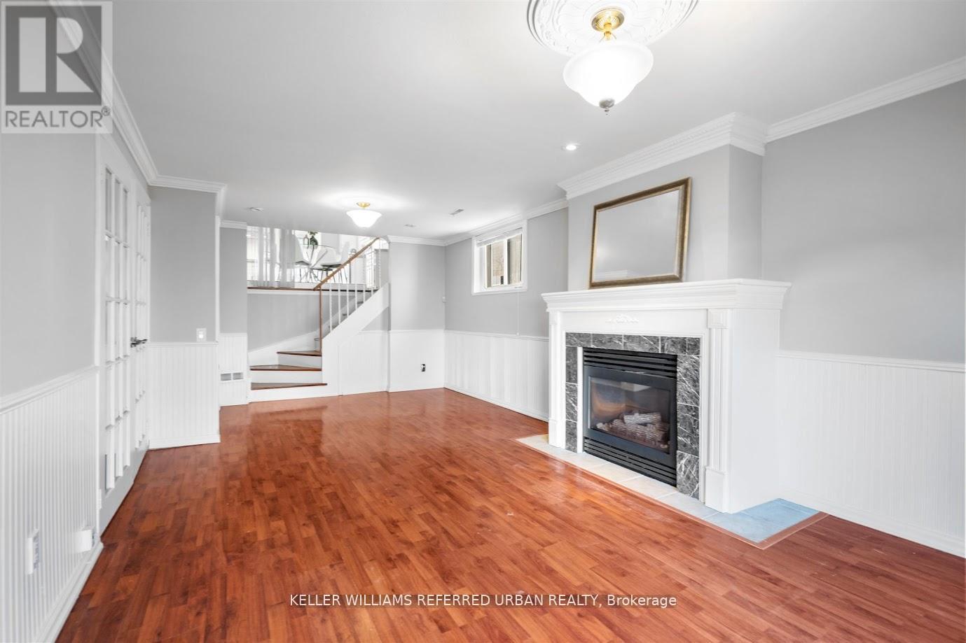 A spacious room with a fireplace and wood flooring.