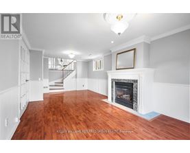 A spacious room with a fireplace and wood flooring.