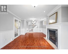 A spacious living room with wood flooring and a fireplace.