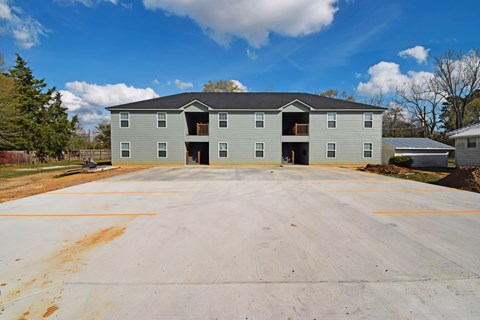 A large grey building with a parking lot in front.