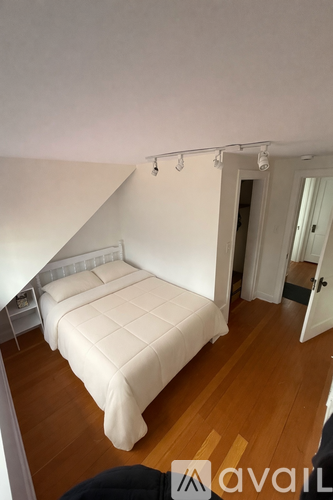 A bedroom with a bed and a wooden floor.